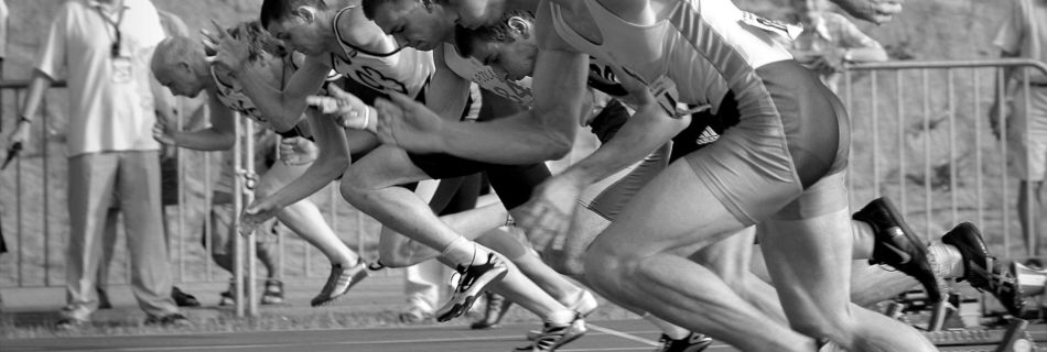 athletes running on track and field oval in grayscale photography